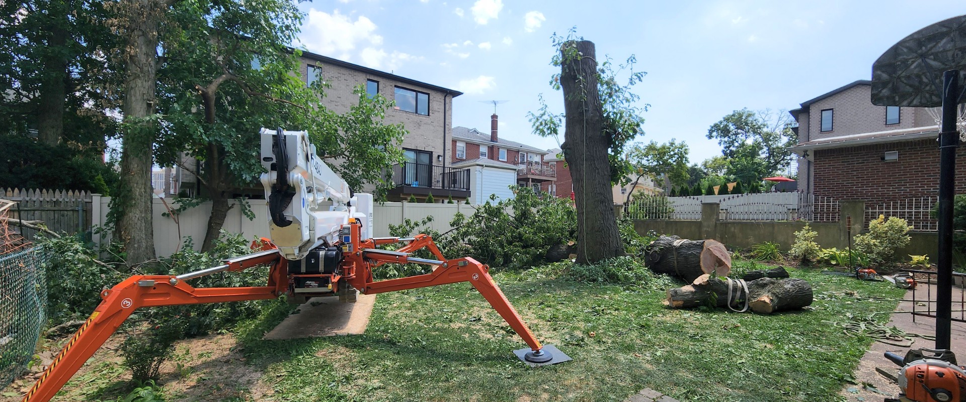 The Aspen Tree spider lift sitting near cut logs during a tree removal job in Montclair, NJ.