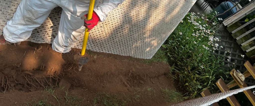 Fixing a Common Cause of Tree Decline with Air Spading and Root Collar Excavation 1 An arborist using a yellow air spading tool to carefully excavate soil around the base of a tree trunk, revealing the root collar area.